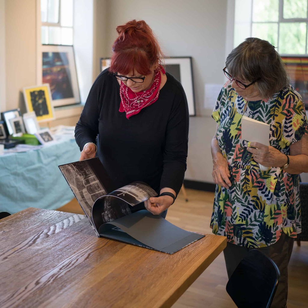 A photograph of two people looking through a book.