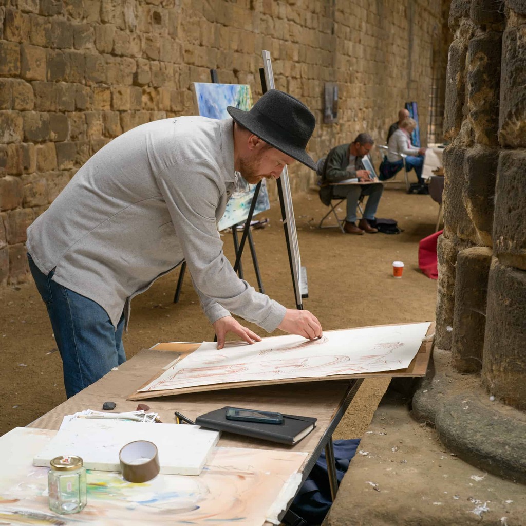 A photograph of a person drawing, inside Kirkstall Abbey