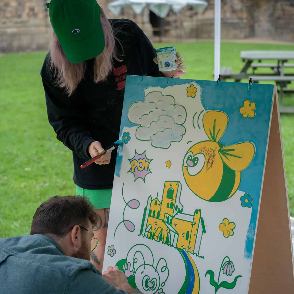 A photograph of two people painting a board