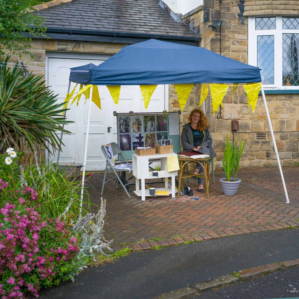 a photograph of a person sitting under a gazebo, on the driveway of a house