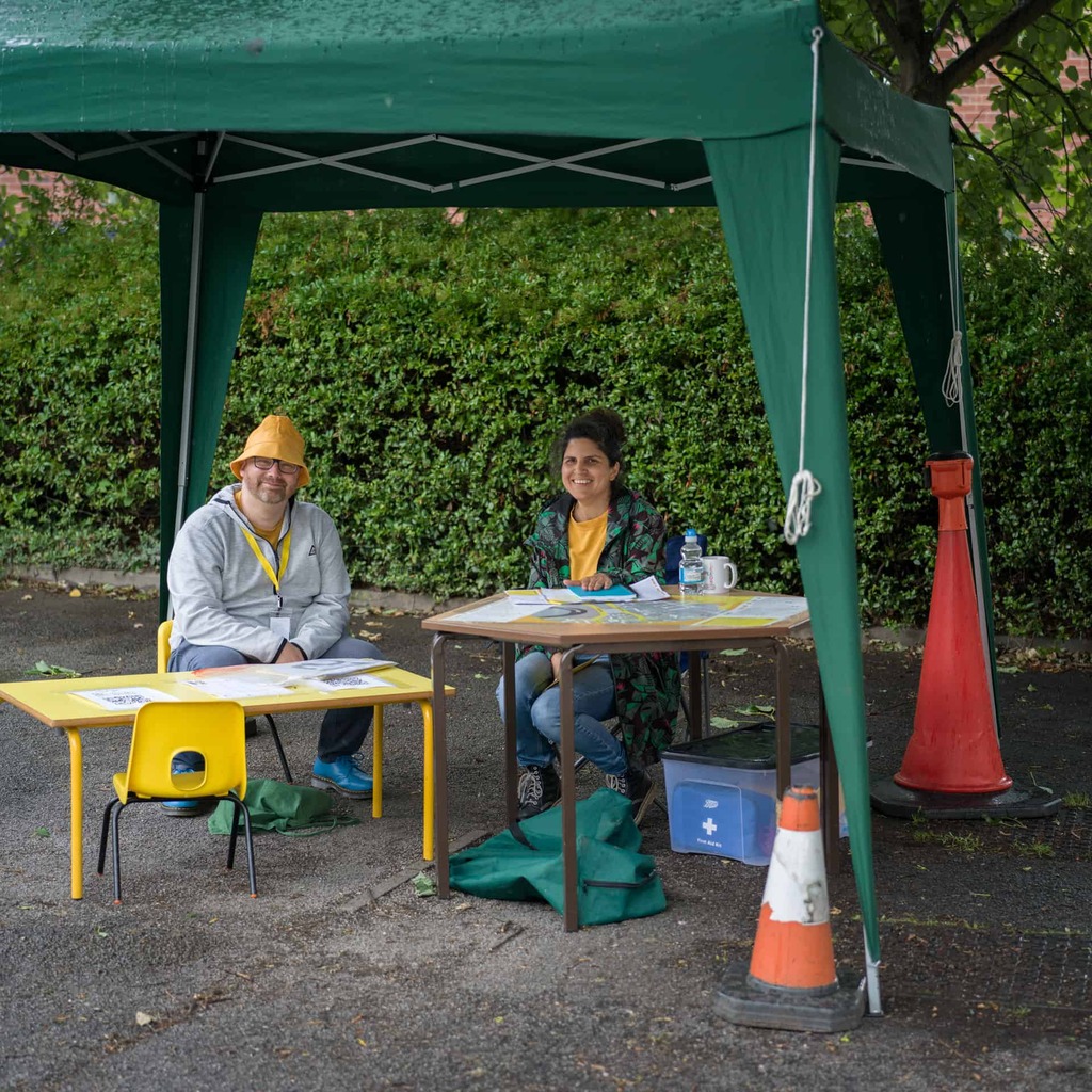 a photograph of two people sitting at tables under a gazebo.