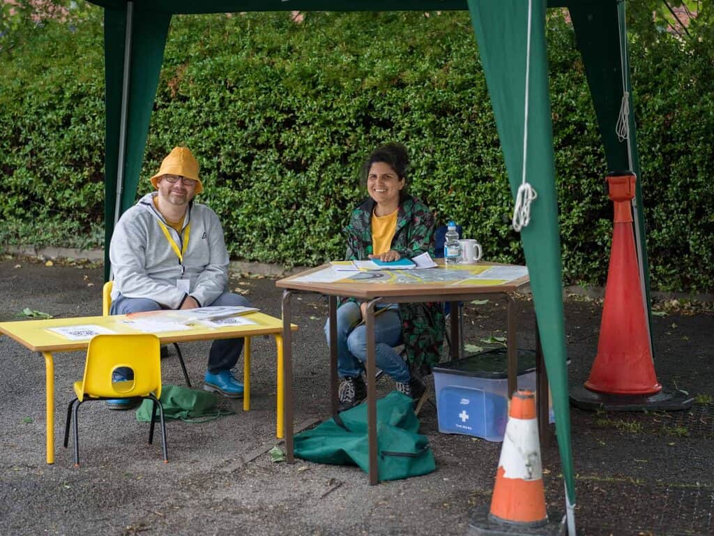 a photograph of two people sitting at tables under a gazebo.