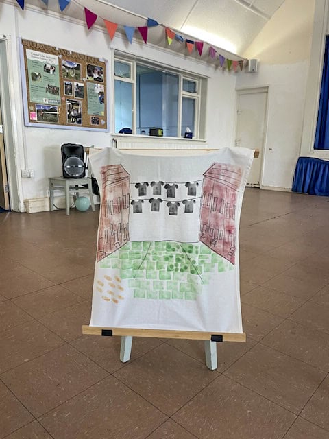 A white t-shirt with art work drawn on it, displayed on a frame