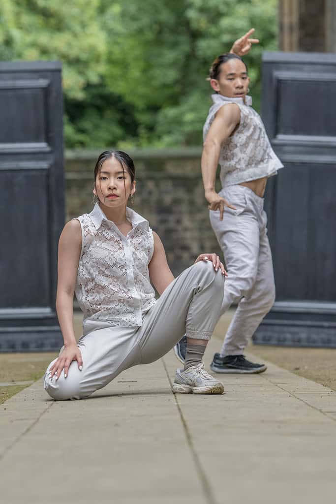 Two dancers perform. They wear sleeveless lace shirts that were created by one of the designers.