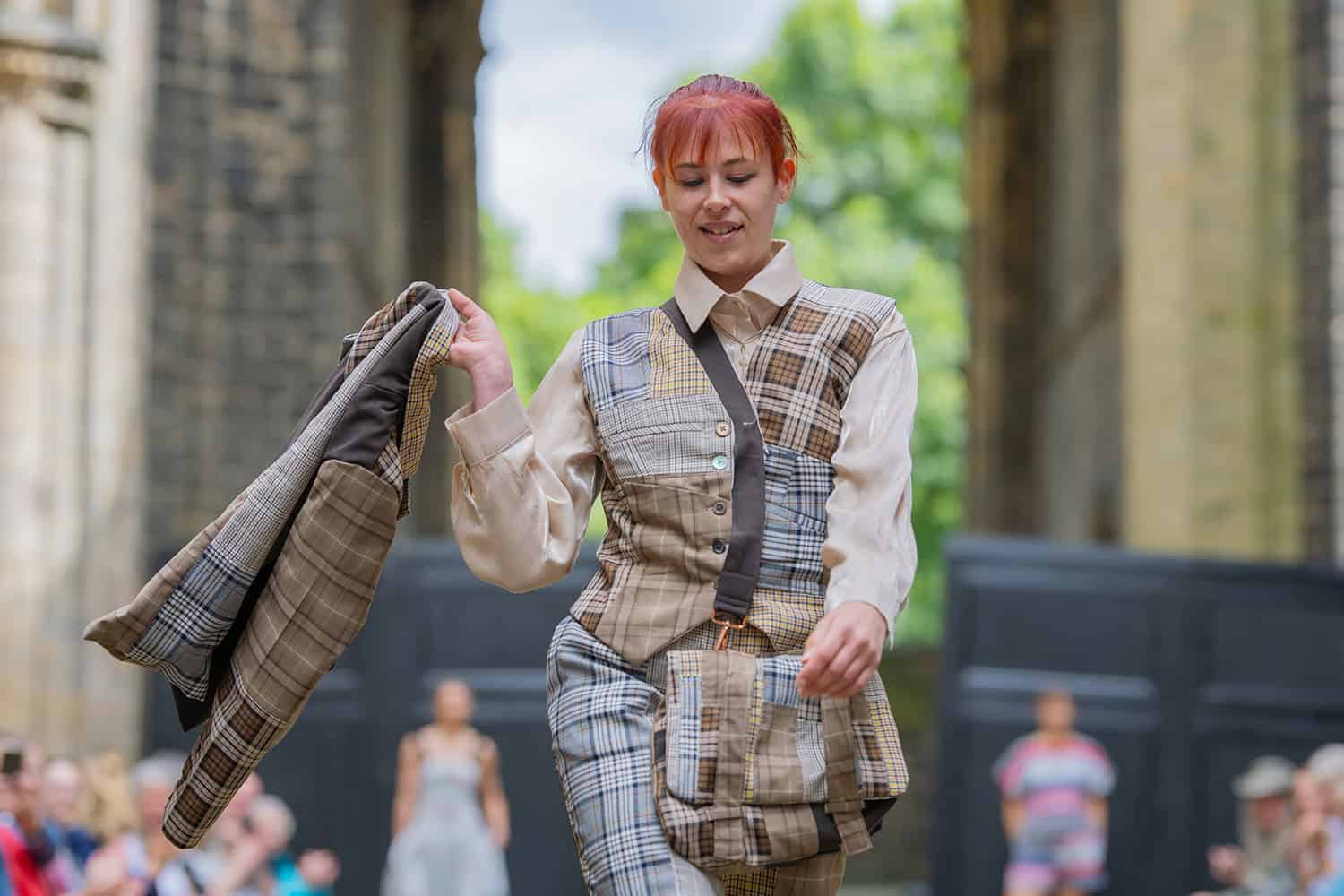 The model wears a three piece suit. They carry their jacket and have a matching cross body bag