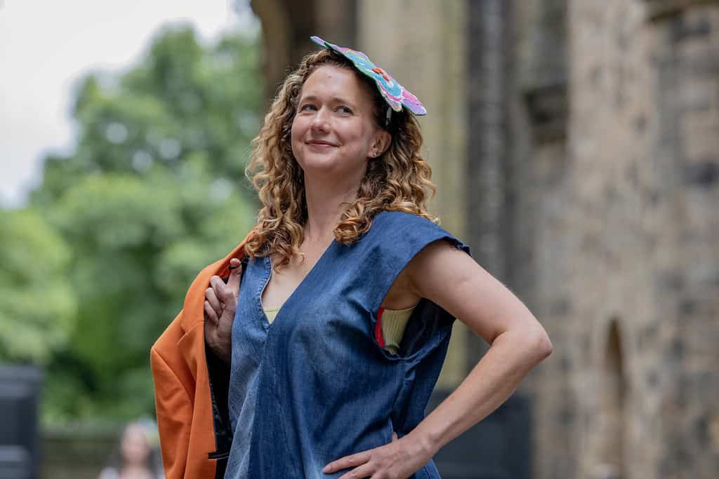 The model is dress in denim and carries a jacket. They are also wearing a fascinator cut out from patterned fabric