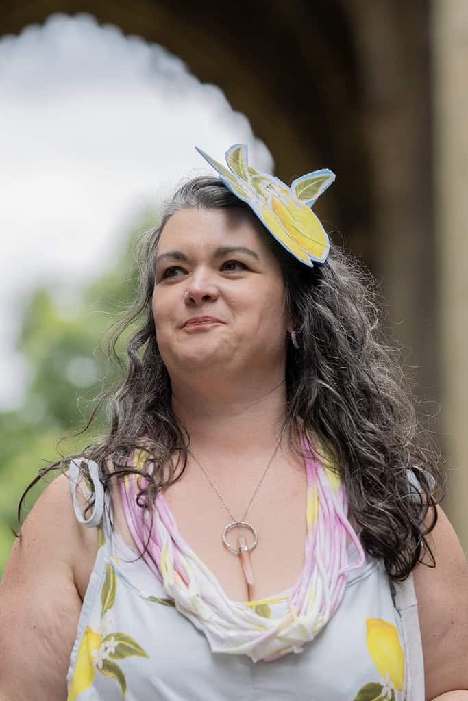 The model wears a fascinator that has been created from part of the pattern that is also seen on the dress they wear.