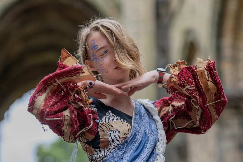 The model poses with their hands under their chin.