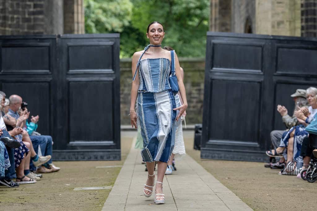 The model wears a matching top and skirt created from different pieces of denim