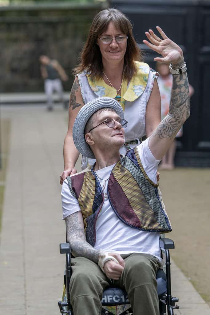 There are two models. The first in in a wheelchair waving to the audience, they wear a waistcoat made from ties. The other is pushing the chair and wears a dress