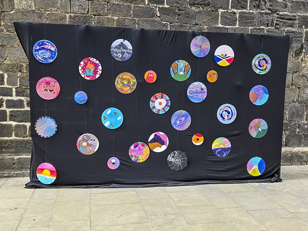 Hand-painted vinyl discs displayed on black cloth.