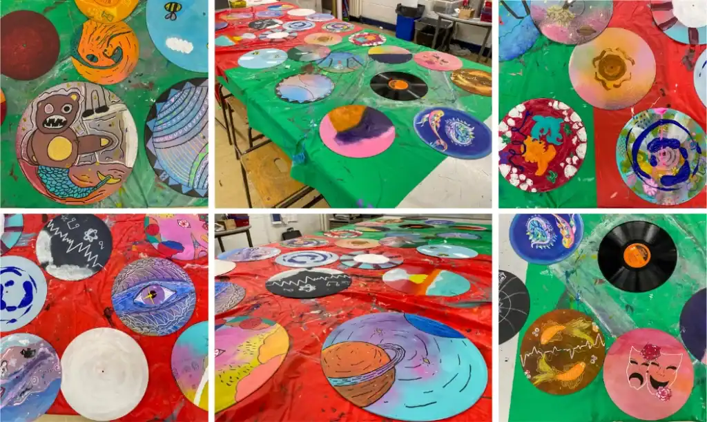 Collage of hand-painted vinyl record discs in progress, featuring space and planet designs, characters, and an eye motif.